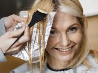 Smiley-woman-getting-her-hair-dyed-by-hairdresser-home-spotlisting